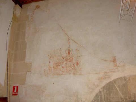 Home fent volar estel per damunt una església, escuts, esfinx i altres